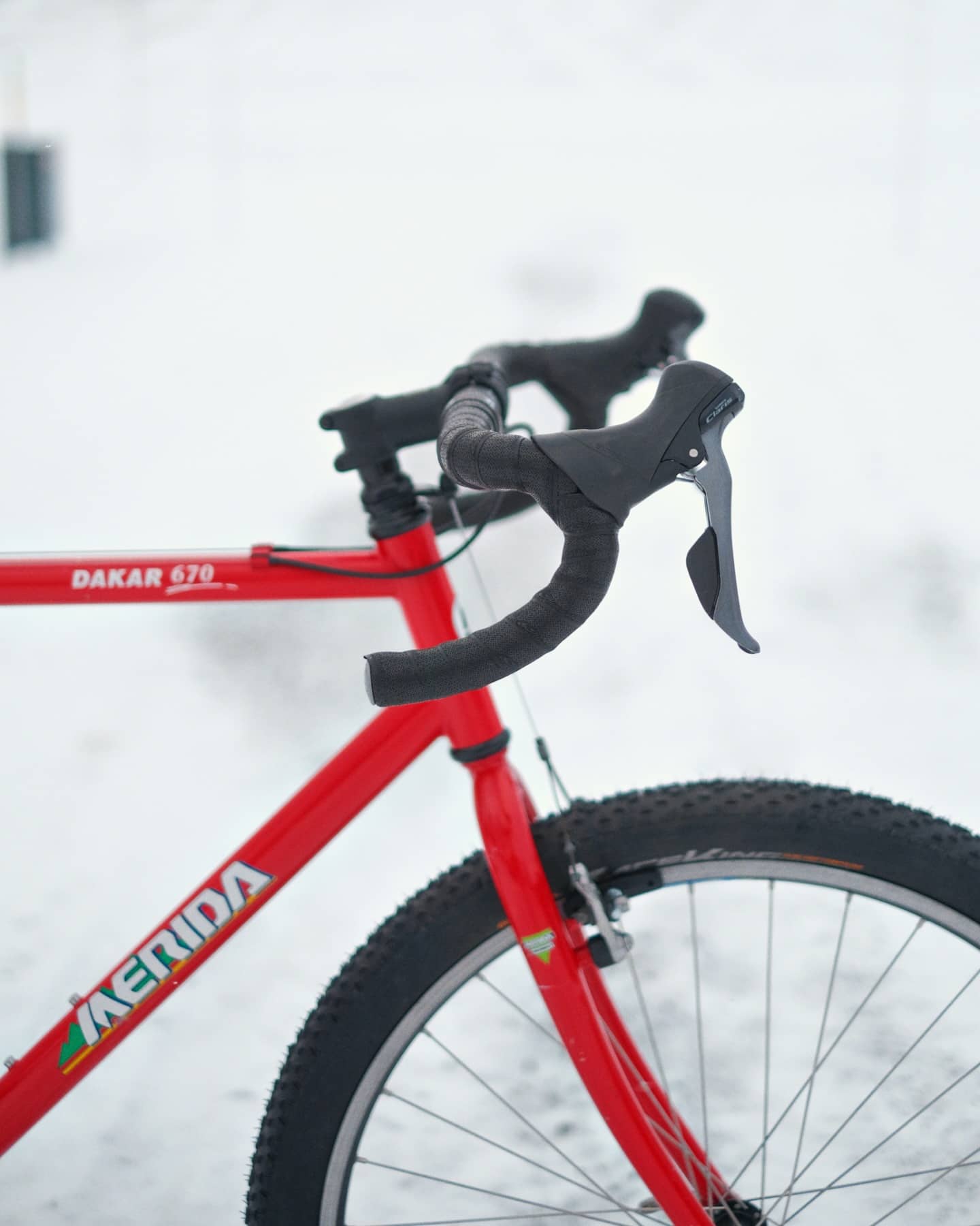 Close view of the red frame showing the Dakar 670 decal on the top tube, the Merida logo on the down tube and the black-taped drop bar.