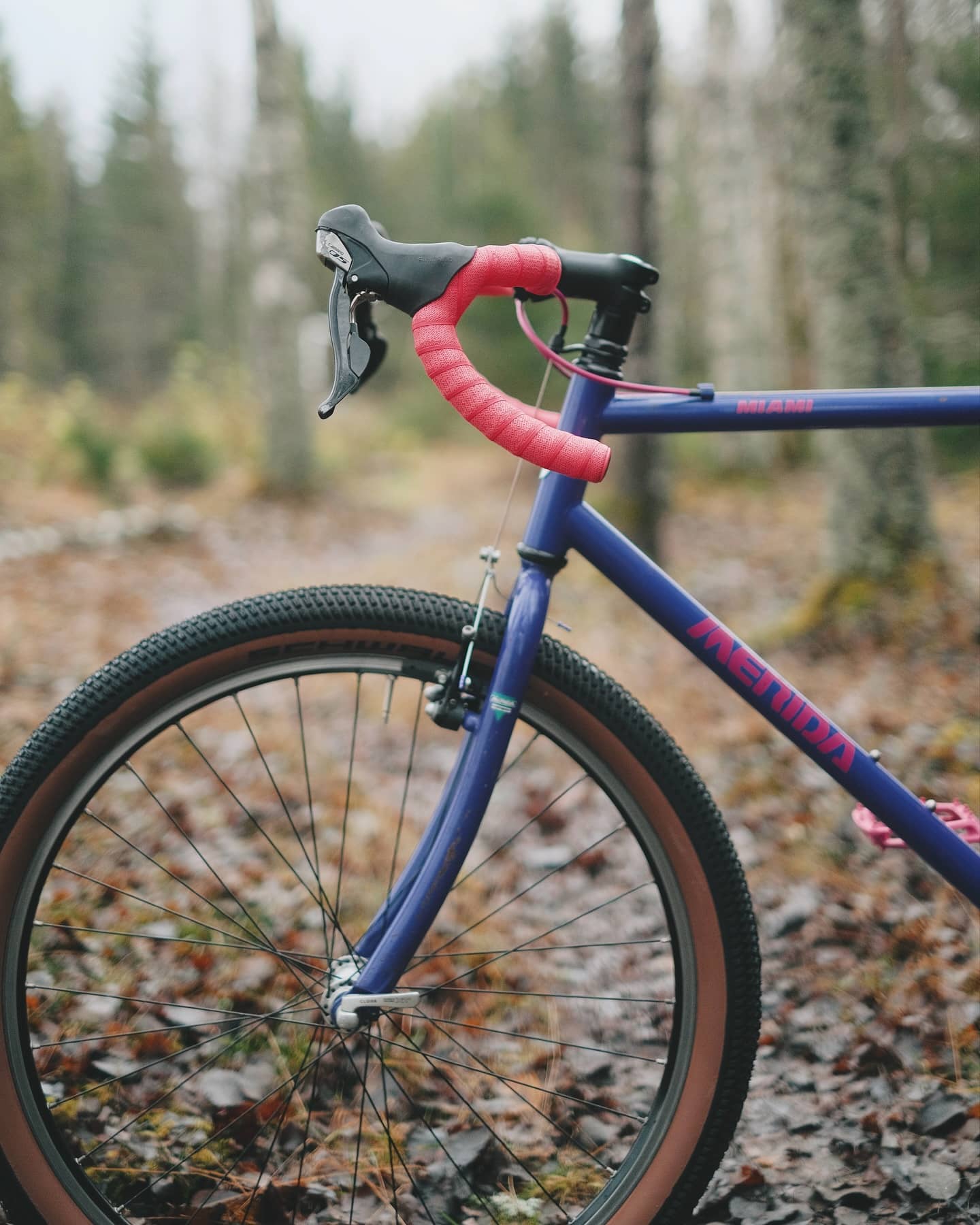 Close view of the cockpit: the pink-taped drop bar, brake lever and the red Merida decal on the purple down tube.